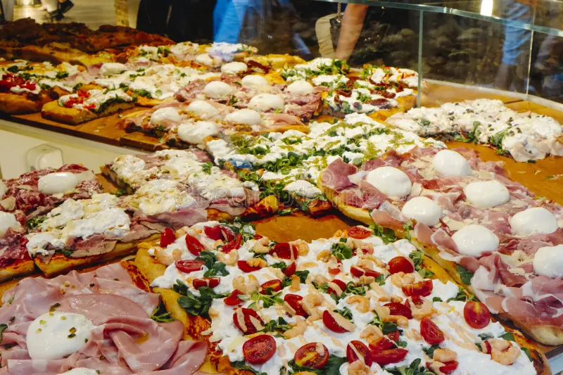 Italian Pizza al Taglio in a store on wooden planks.