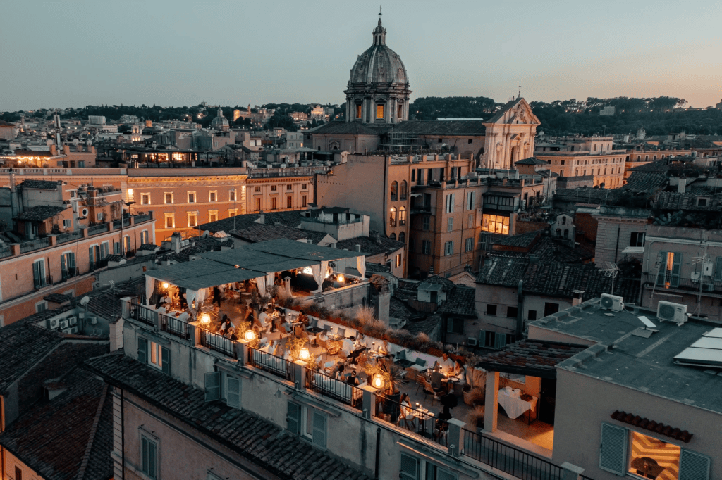 The Vista Rooftop Roma during the sunset with the lights turned on.