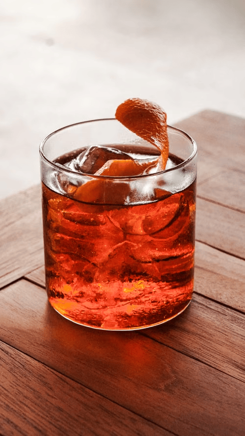 A ice cold negroni drink on a wooden table.